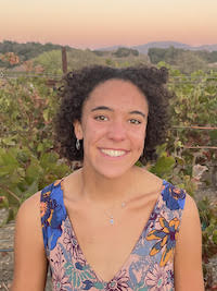 Madeleine standing in a vineyard at sunset.